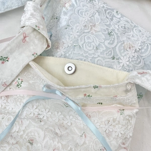 Close-up of floral lace shoulder bag with silk ribbon bows and silver magnetic snap closure