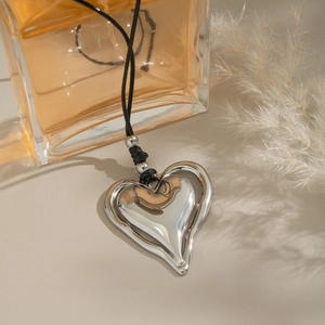 Détail du pendentif en forme de cœur argenté avec cordon noir et perles argentées