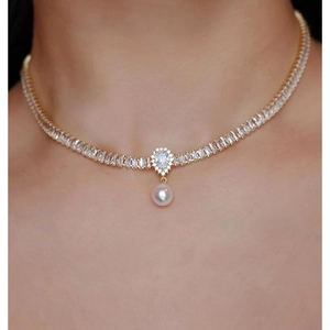 Dettaglio della collana in cristallo dorato con zircone a goccia e perla bianca