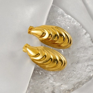 Elegant gold shell teardrop earrings with textured wave pattern on a white silk background