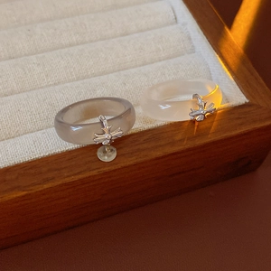 Detail of gray and white chalcedony rings with silver cross pendants in a wooden box