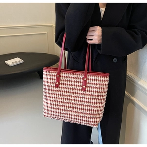 Close-up of red and white houndstooth tote bag with leather handles and gold metal rivets