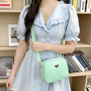 Pale green woven camera bag for women with metal logo plate and wide shoulder strap