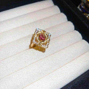Macro shot of gold-plated vintage ring featuring red oval gemstone and zircon pavé