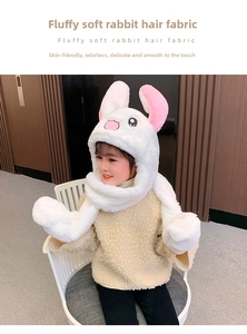 Close-up of white plush rabbit ear hat with scarf and gloves on a child model