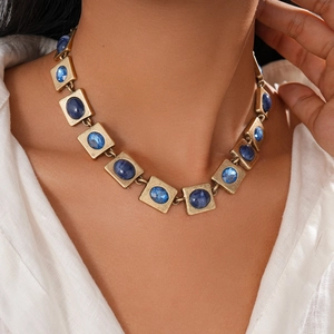 Nahaufnahme einer Vintage-Goldkette mit blauen quadratischen Edelsteinen an einem Model