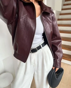 Gros plan sur la texture du blouson aviateur bordeaux et le détail du zip argenté
