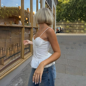 Street style view of a white lace ruffled camisole top paired with classic blue jeans