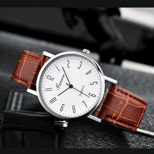 Macro shot of silver quartz watch with white dial and brown leather crocodile strap