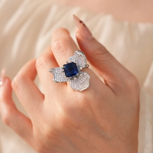 Macro detail of floral ring featuring a square blue zircon and pavé diamond petals
