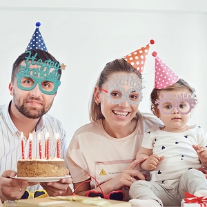 Family celebrating birthday with glittery Happy Birthday glasses and colorful party hats