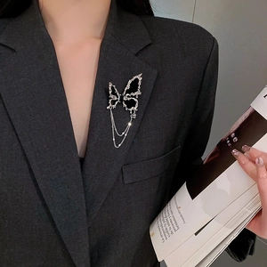 Vue détaillée d'une broche papillon argentée avec ailes noires et pompons sur un costume