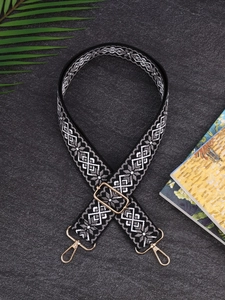 Detail of black and white geometric pattern bag strap with gold metal swivel hooks