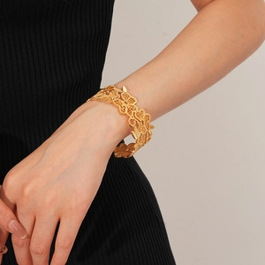 Detailansicht eines vergoldeten Blumenarmbands mit feinen hohlen Blüten und Metalltextur
