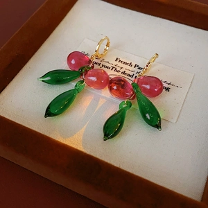 Détails de boucles d'oreilles baies en verre avec feuilles vertes et anneaux dorés