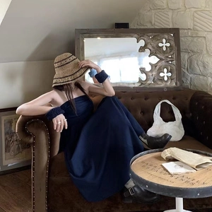 Strohhut im französischen Stil mit dunkelblauem Kleid in Vintage-Innenszene