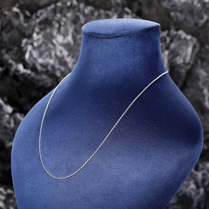 Macro detail of silver link chain necklace displayed on blue velvet jewelry stand