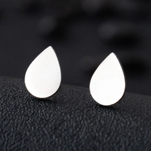 Macro shot of silver teardrop stud earrings on a textured black background surface