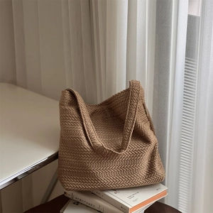 Brown woven tote bag with herringbone texture on stacked books in natural soft light