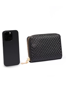 Detail of black glossy patent leather wallet with diamond lattice texture and gold zipper