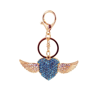 Exquisite golden winged heart keychain with blue rhinestones on a white background