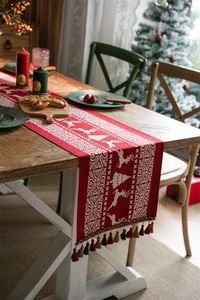Detailed close-up of a red Christmas table runner with reindeer motifs and tassel fringe
