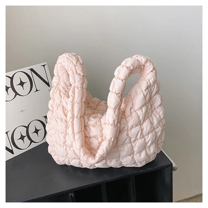 Detailed texture of a light pink quilted puffy handbag with a soft cloud-like bubble grid