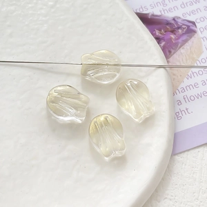 Macro shot of 4 sparkling shell-shaped beads for DIY jewelry making on a textured plate