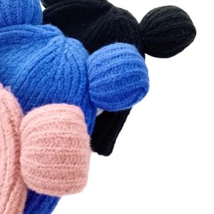 Close-up of thick knit beanies showing pink, blue and black textures and cute ear detail