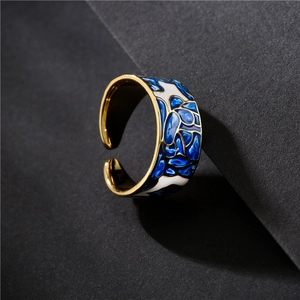 Adjustable golden ring with blue and white enamel floral pattern on grey background