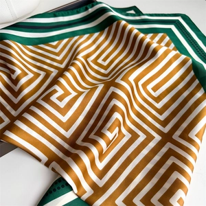 Détail du foulard en soie aux motifs géométriques jaune et vert avec bords rayés