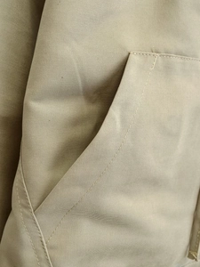 Detailed close-up of side pocket stitching on beige cropped drawstring jacket