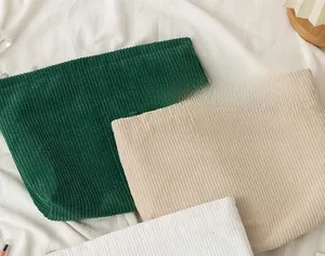 Close-up of corduroy toiletry bags in dark green and beige with ribbed texture detail