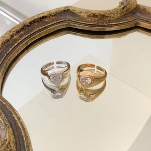 Detail of minimalist gold and silver rings with heart-shaped zircon on a mirror tray