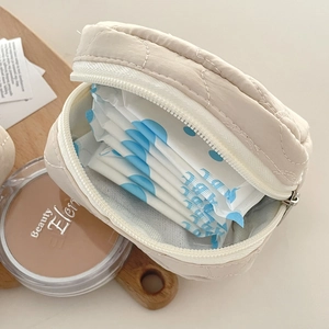 Quilted beige cosmetic bag with zipper showing sanitary pad storage in a round pouch