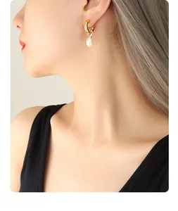 Detailed view of Baroque pearl C-shaped earrings in gold on a model's ear