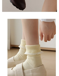 Detail of pale yellow ribbed crew socks with lettuce edge cuffs paired with Mary Jane shoes