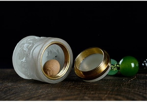 Macro shot of an ivory-colored lotus jar with a gold metal cap and green bead charm