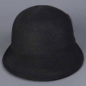 Dettaglio del cappello di paglia nero con trama a spirale e decorazione in piuma
