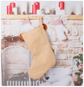 Beige knitted Christmas stocking with bear ears hanging on a cozy decorated fireplace