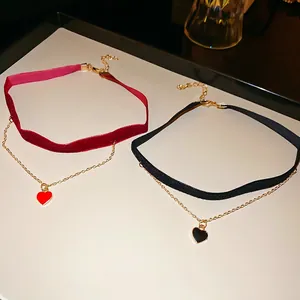 Elegant velvet choker set with red and black enamel heart pendants on a white tray