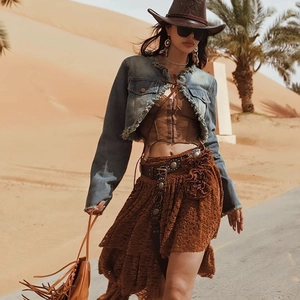 Western style women's denim jacket and lace skirt outfit with cowboy hat in desert
