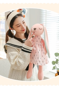 Close-up of pink plush rabbit doll with long ears and patterned dress in soft natural light