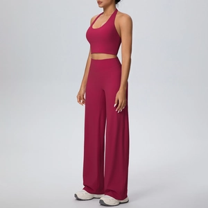 Side view of woman in burgundy halter yoga crop top and high-waisted wide-leg sports pants