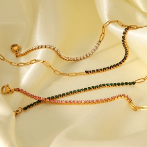 Detailed view of colorful zircon crystals on gold cross chains over silk fabric
