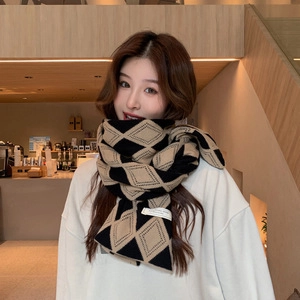 Detail of soft black and beige argyle knit scarf with fringe and a small white woven label