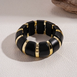 Close-up of chunky acrylic stretch bracelet in contrasting black and gold block design