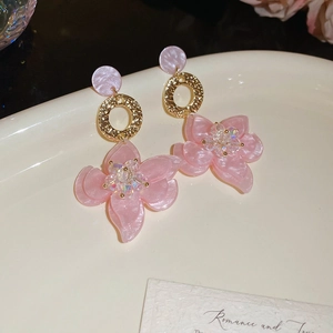 Detail von rosa Harz-Blumenohrringen mit Goldring und Perlenmitte auf Tablett