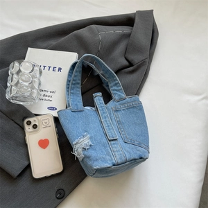 Distressed blue denim tote bag with vintage wash and pocket detail on a stylish background