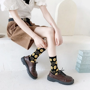 Detail of black crew socks with yellow smiley faces worn with leather shoes and corduroy